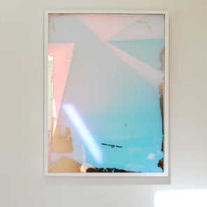 A multi-colored fine art mirror hangs on a white wall. 