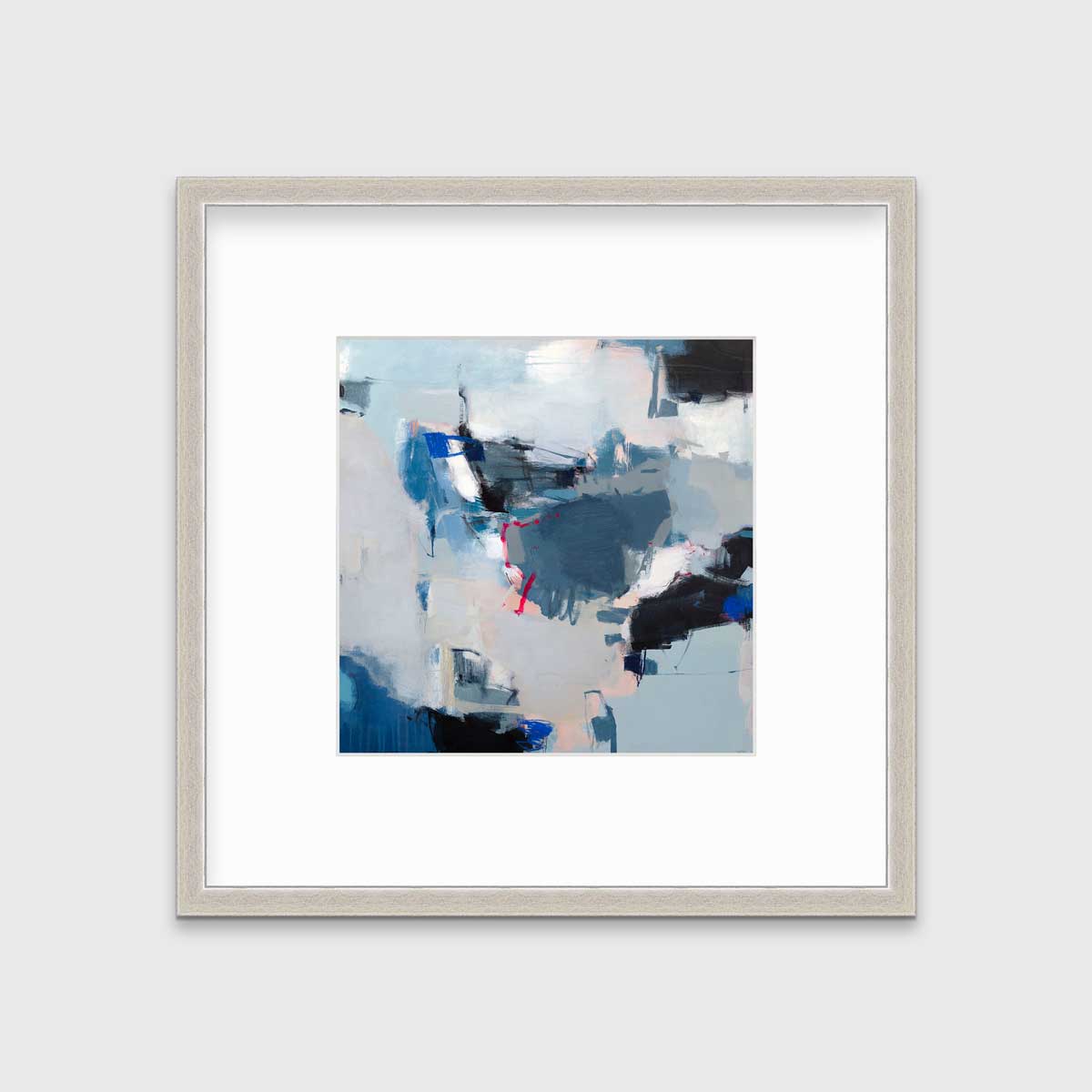 A blue abstract print by Kelly Rossetti in a silver frame with a mat hangs on a white wall.
