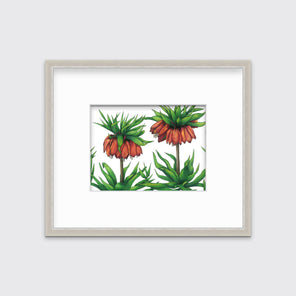A green and red-orange floral print in a silver frame with a mat hangs on a white wall.