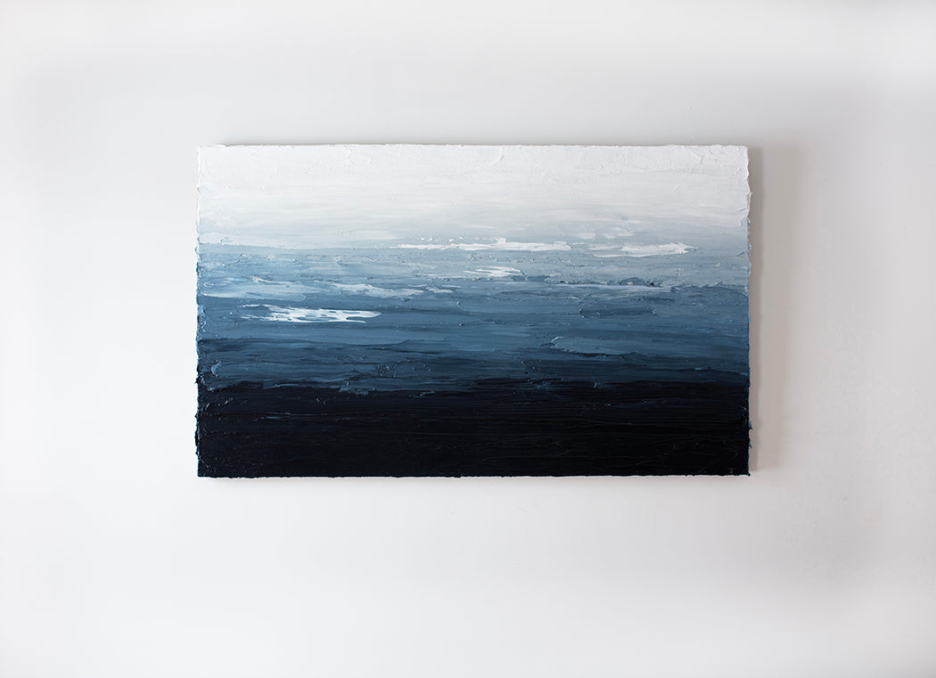 A blue, white and navy abstract painting by Teodora Guererra very textured abstract painting hangs on a white wall.