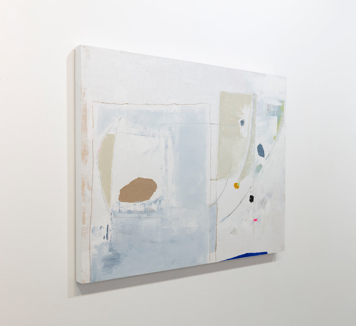 A white abstract painting with lines and multi-colored patches of paint is seen at an angle on a gallery wall. Wired and ready to hang.