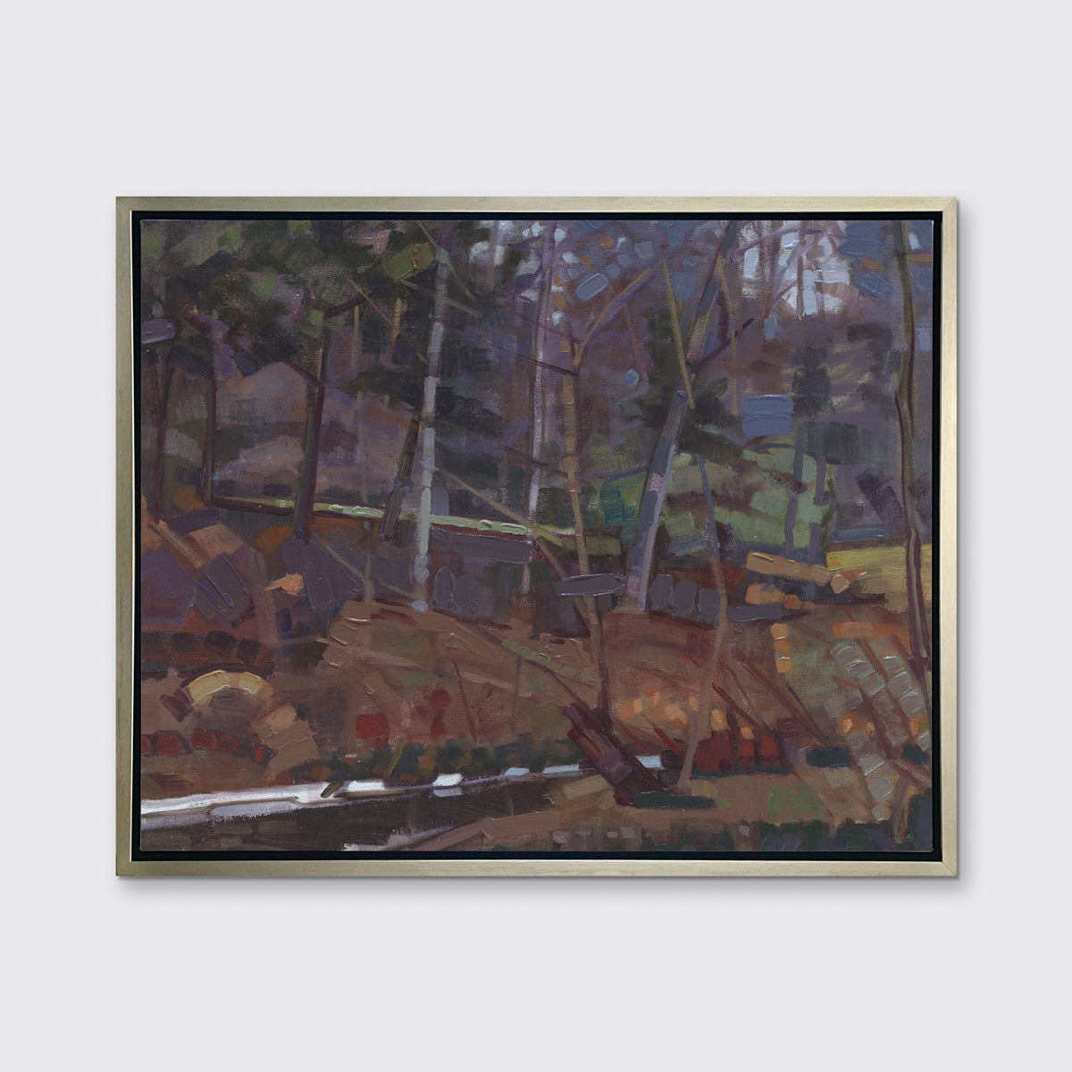 A brown, grey and green abstract landscape print in a silver floater frame hangs on a white wall.