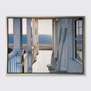 A print of a sunlit porch overlooking the water with two oars and two pairs of shoes on the deck in a silver floater frame hangs on a white wall.