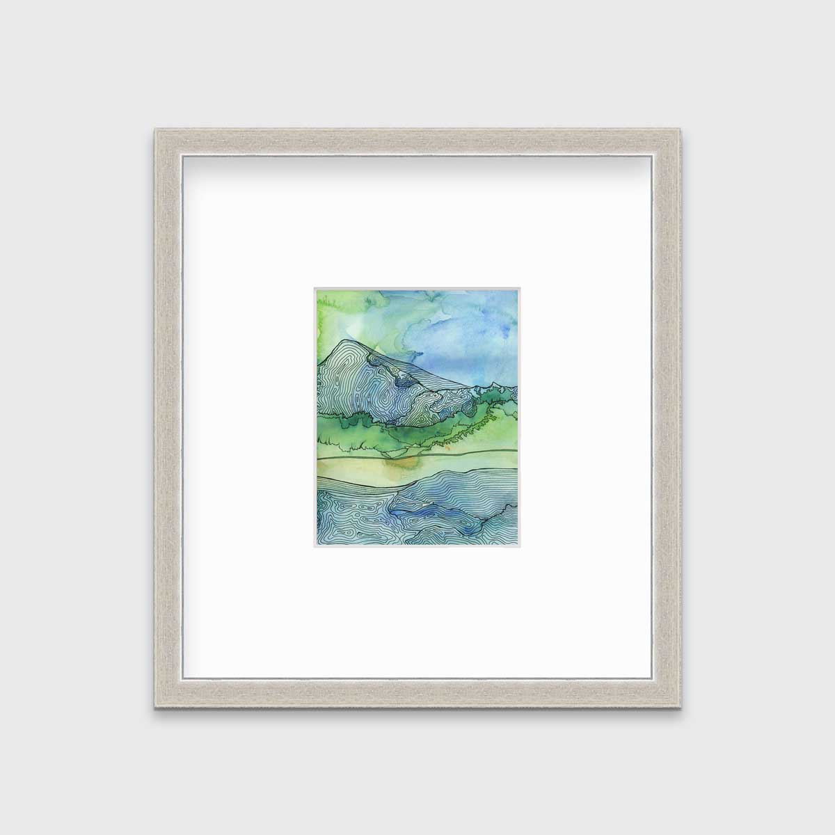 A blue and green landscape illustration print framed in a silver frame with a mat hangs on a light grey wall.