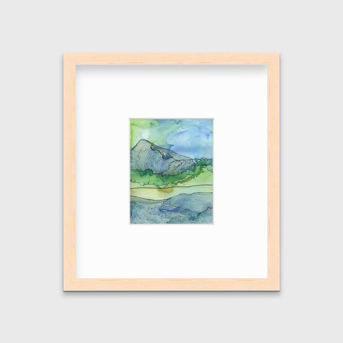 A blue and green landscape illustration print framed in a natural wood frame with a mat hangs on a light grey wall.