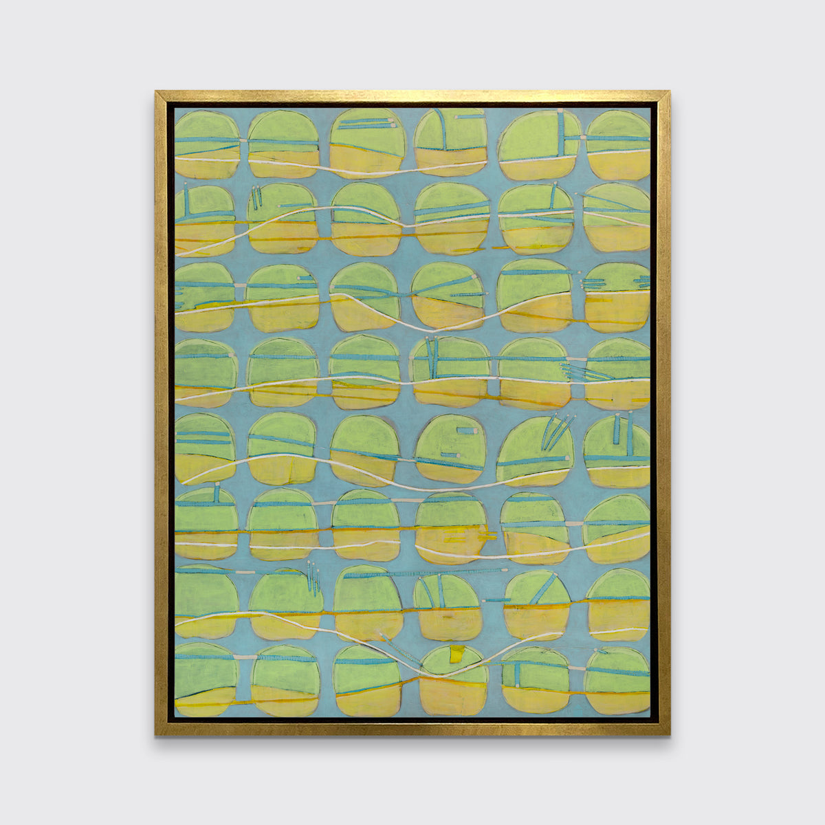 A yellow, green and light slate blue abstract circle print in a gold floater frame hangs on a white wall.