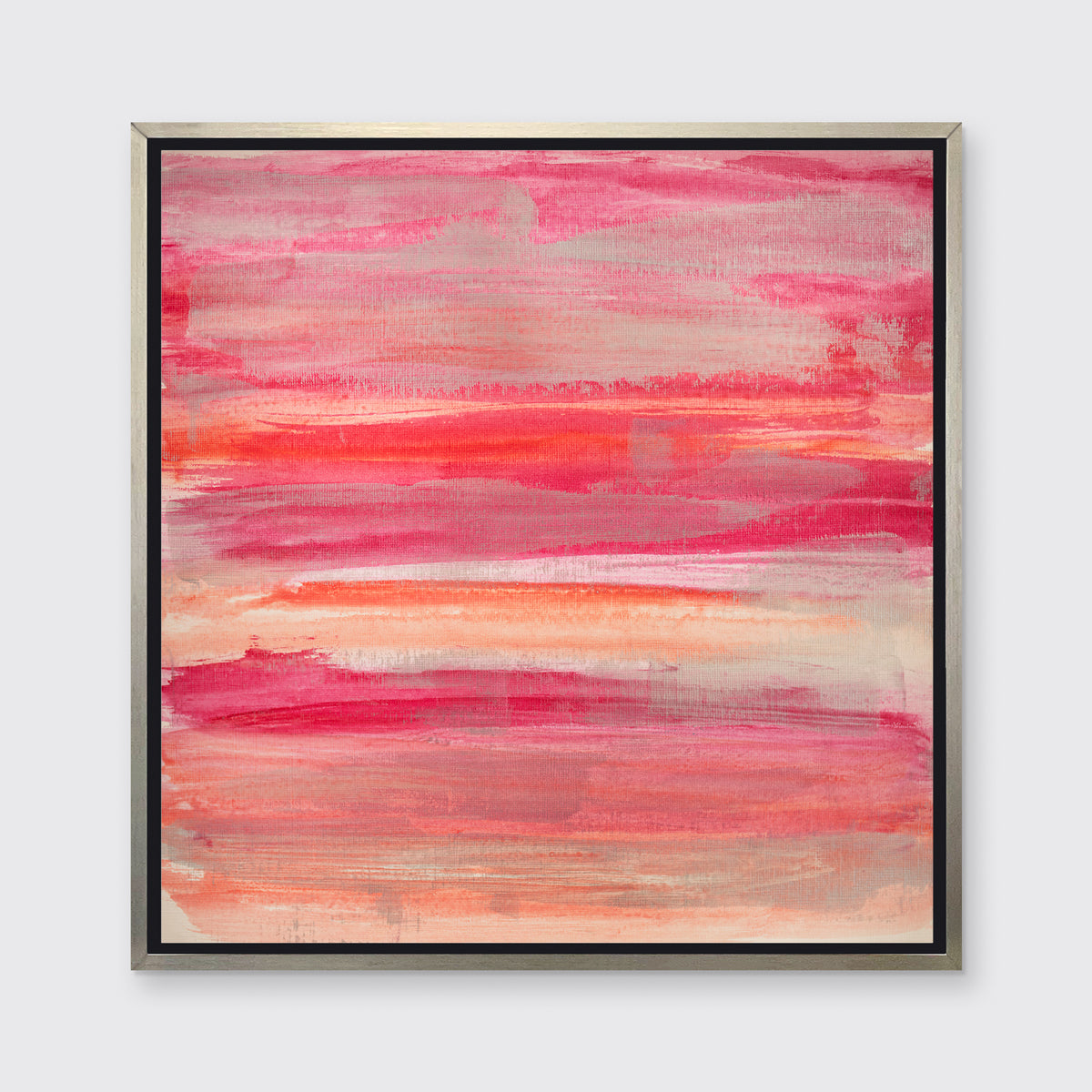 A pink, silver and orange abstract print in a silver floater frame hangs on a white wall.