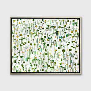 A green, yellow and white abstract print in a silver floater frame hangs on a white wall.