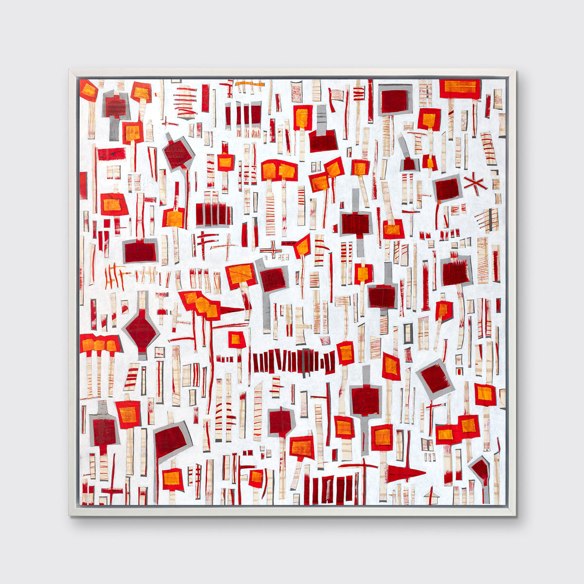A red, white and orange abstract print in a white floater frame hangs on a white wall.