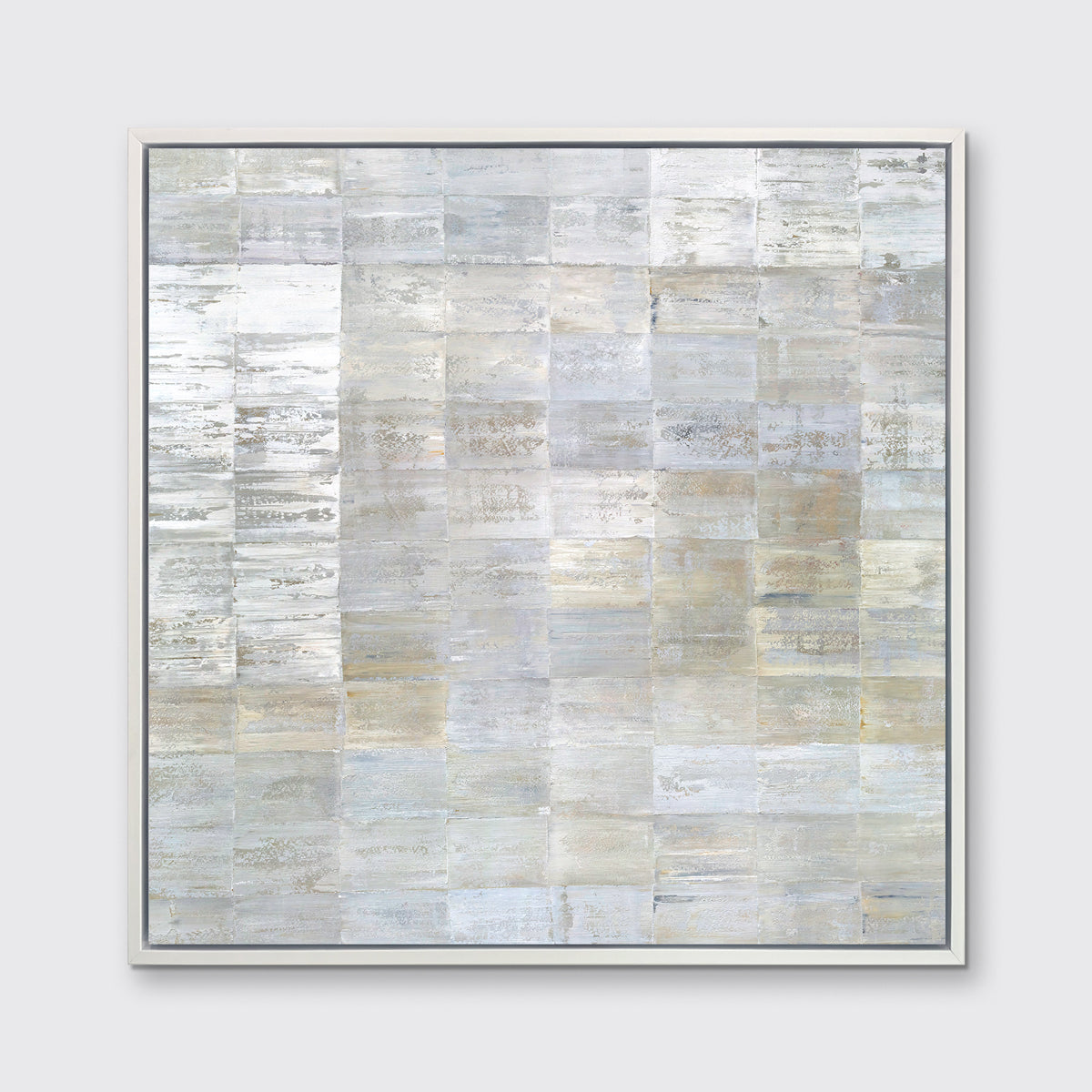 A grey, silver and light gold abstract geometric print in a white floater frame hangs on a white wall.