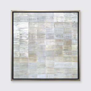 A grey, silver and light gold abstract geometric print in a silver floater frame hangs on a white wall.