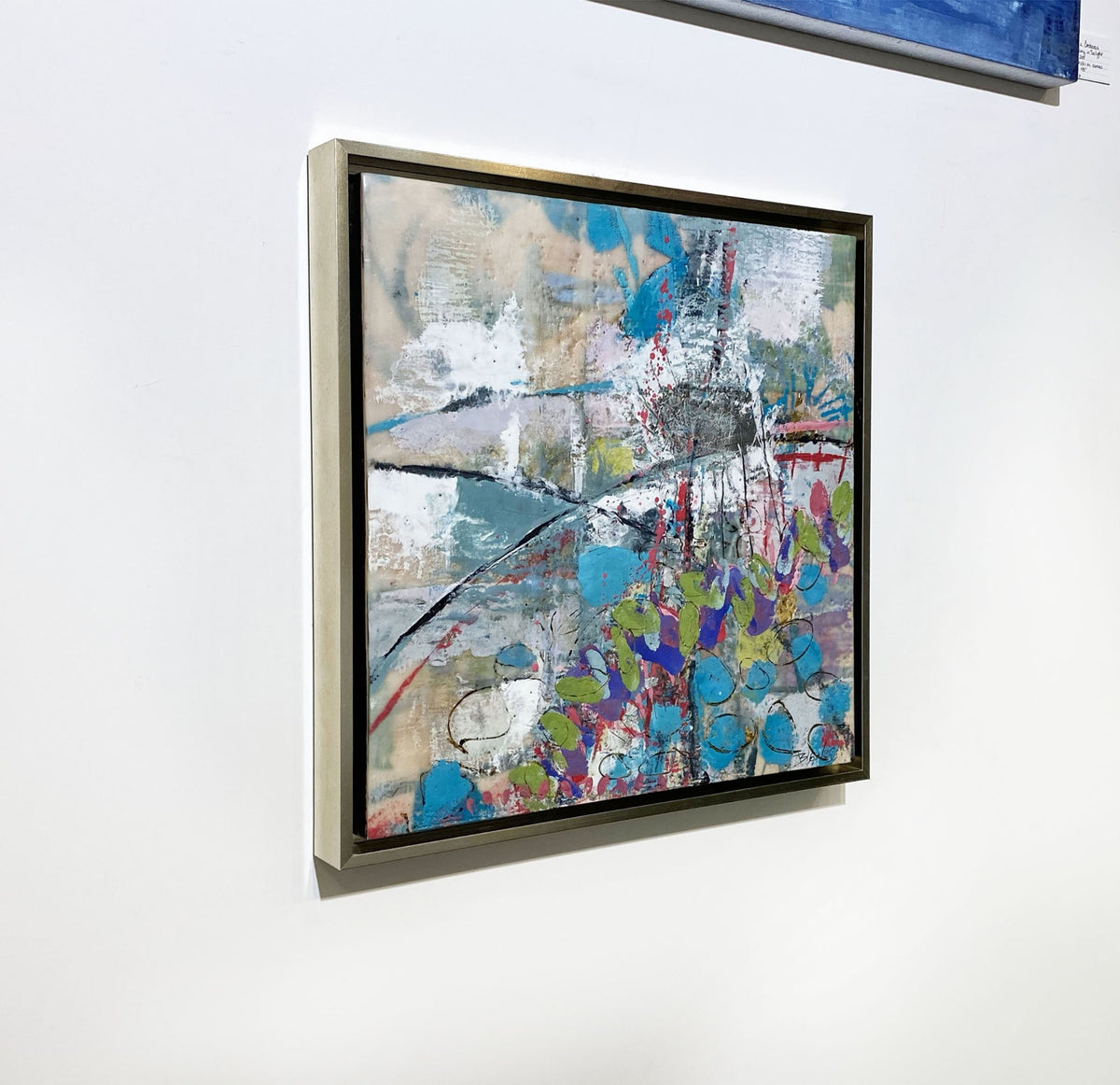 A left-hand side-angle view of an abstract encaustic painting by Linda Bigness, hanging on a white wall.