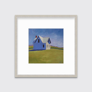 A blue and green contemporary barn print in a silver frame with a mat hangs on a white wall.