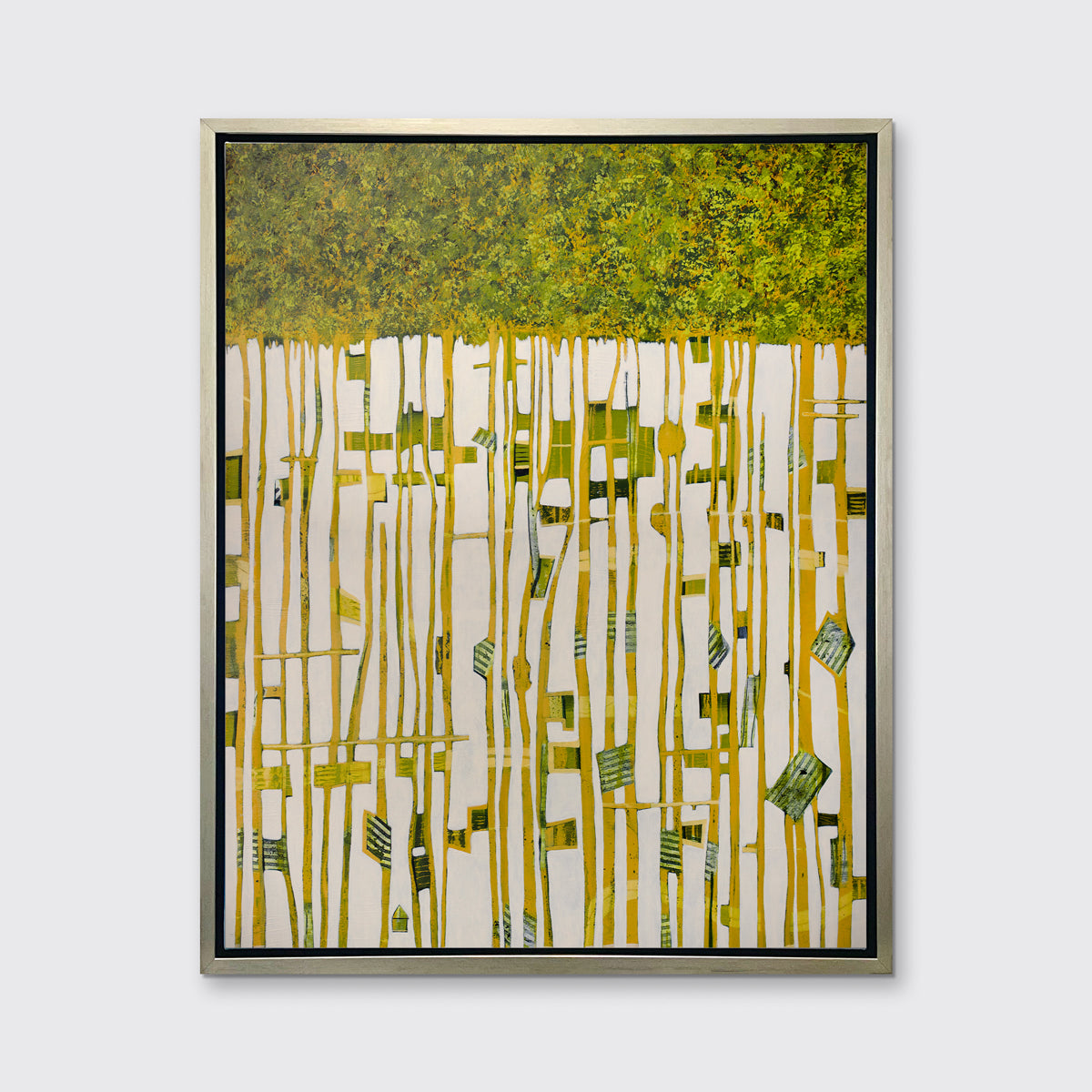 A green, yellow and white abstract print in a silver floater frame hangs on a white wall.