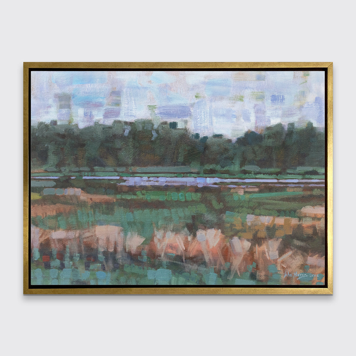 A green, orange and blue abstract landscape print in a gold floater frame hangs on a white wall.