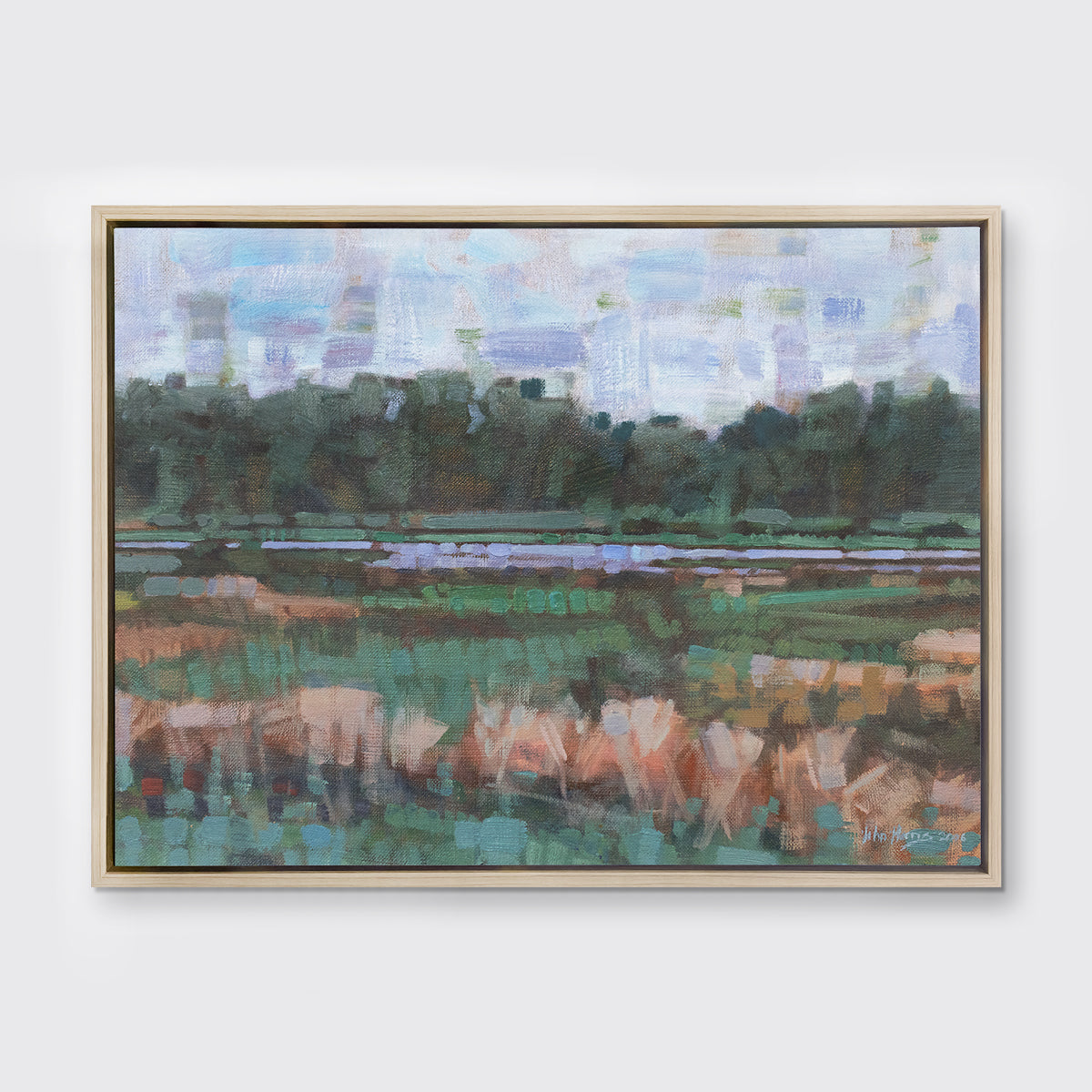 A green, orange and blue abstract landscape print in a white oak wood floater frame hangs on a white wall.