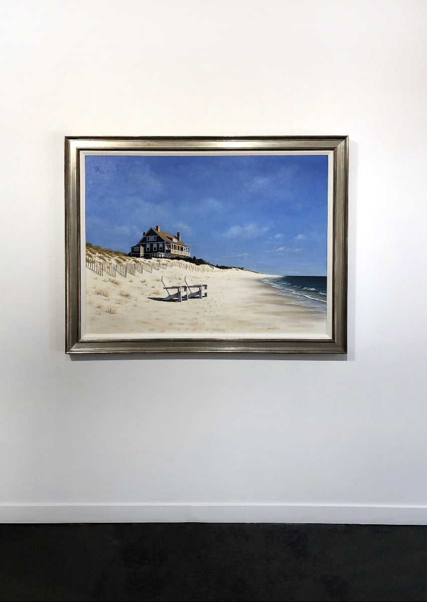 A realist coastal print framed on a white wall.