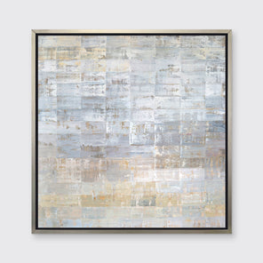 A grey, silver and light gold abstract geometric print in a silver floater frame hangs on a white wall.