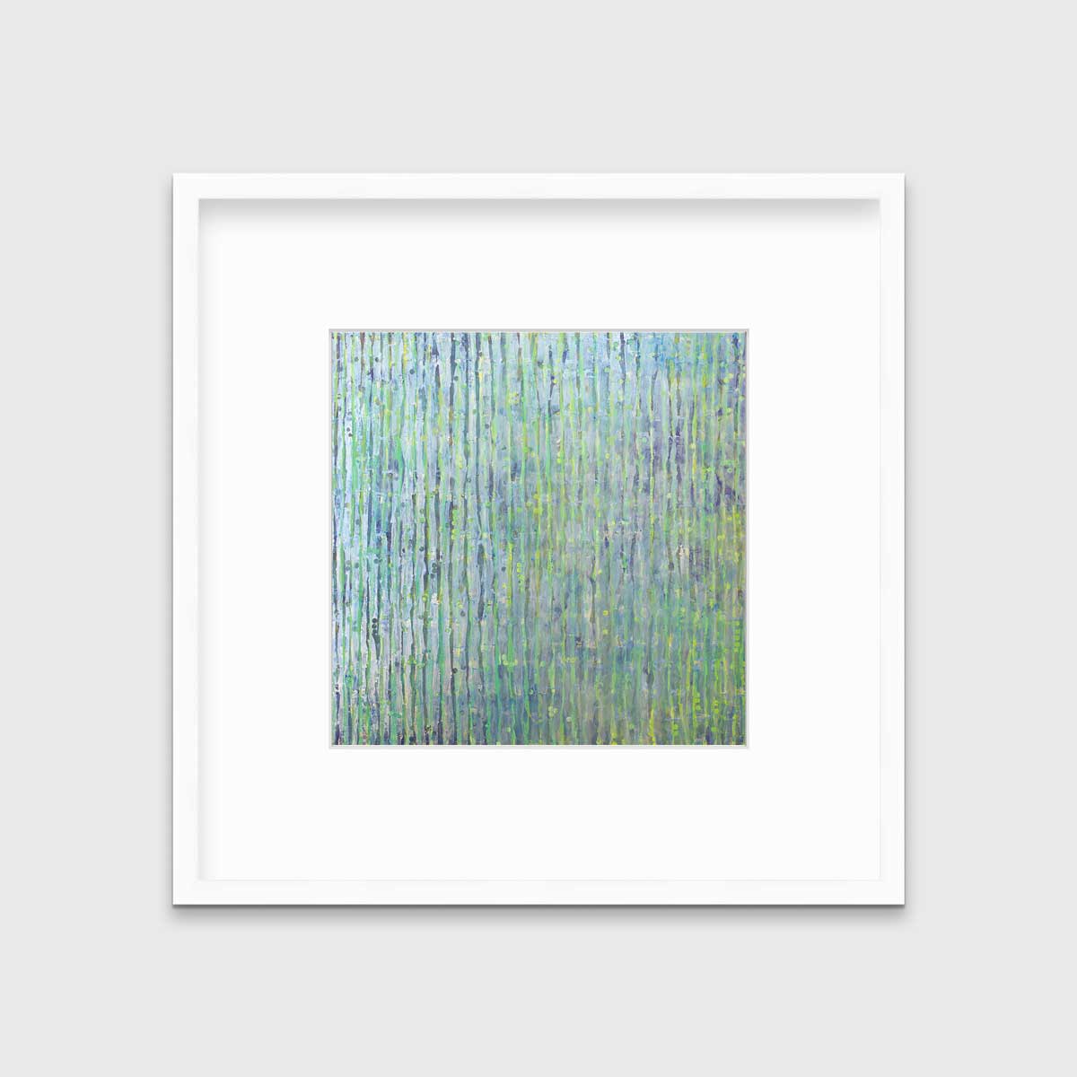 A green, blue and yellow abstract print in a white frame with a mat hangs on a white wall.