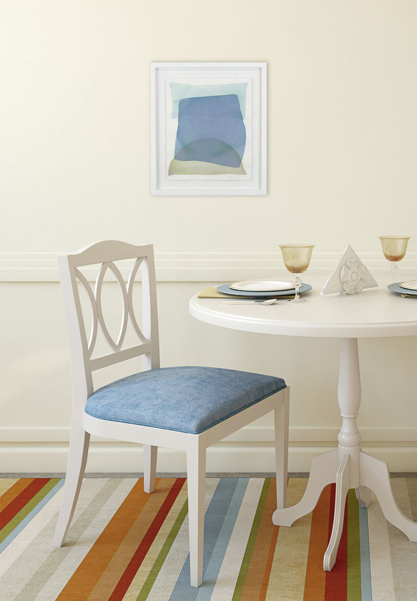 A watercolor of light azure, blue, and yellow forms overlapping is hung in a dining room. Wired and ready to hang.
