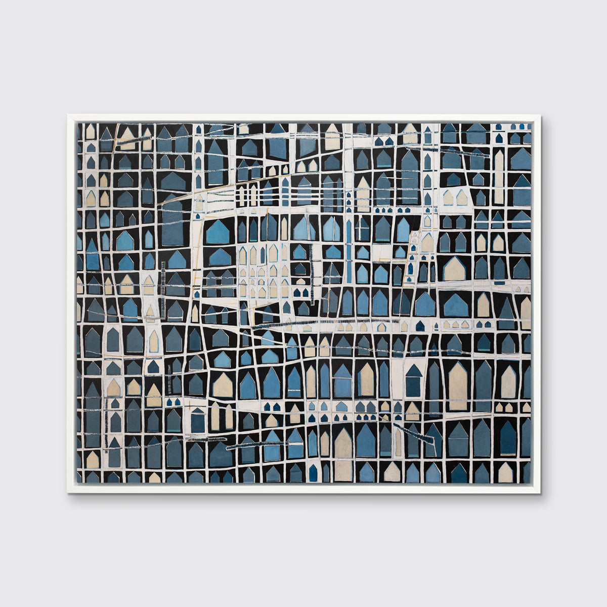 A blue, black, beige and white abstract house print in a white floater frame hangs on a white wall.