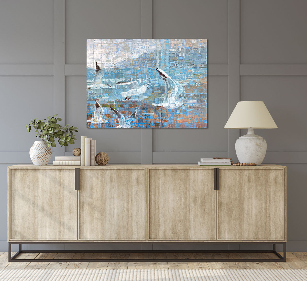 A painting on recycled metal print plates depicting seagulls in flight is hung over a dresser.