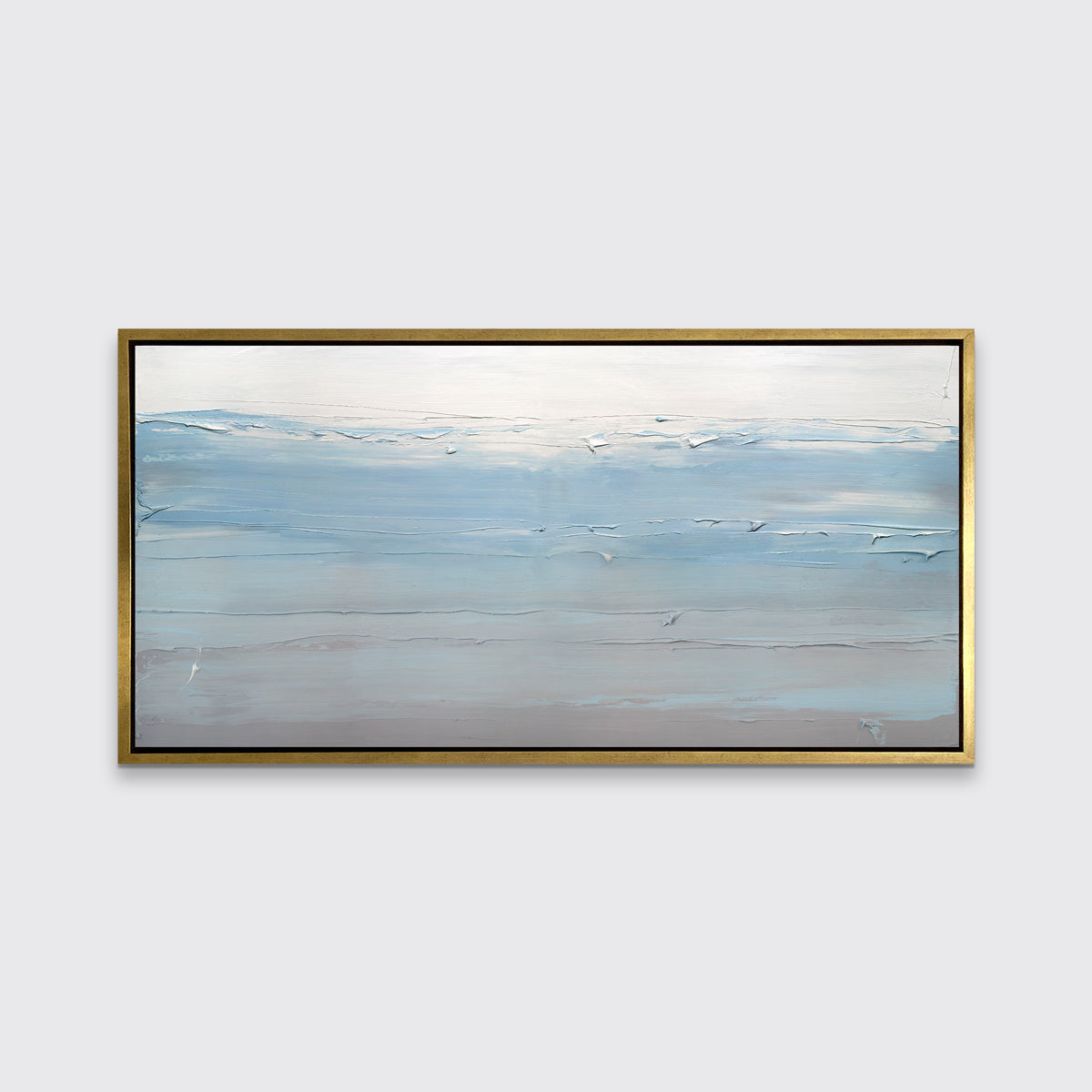 A blue, grey and grey-beige abstract print in a gold floater frame hangs on a white wall.