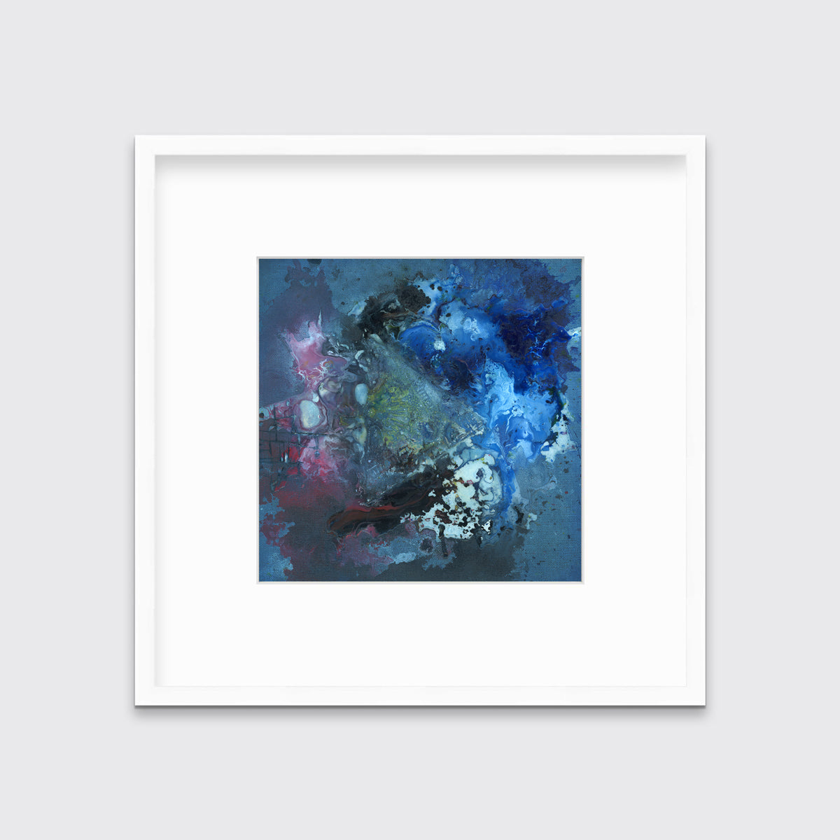 A blue, red, black and green abstract print in a white frame with a mat hangs on a white wall.