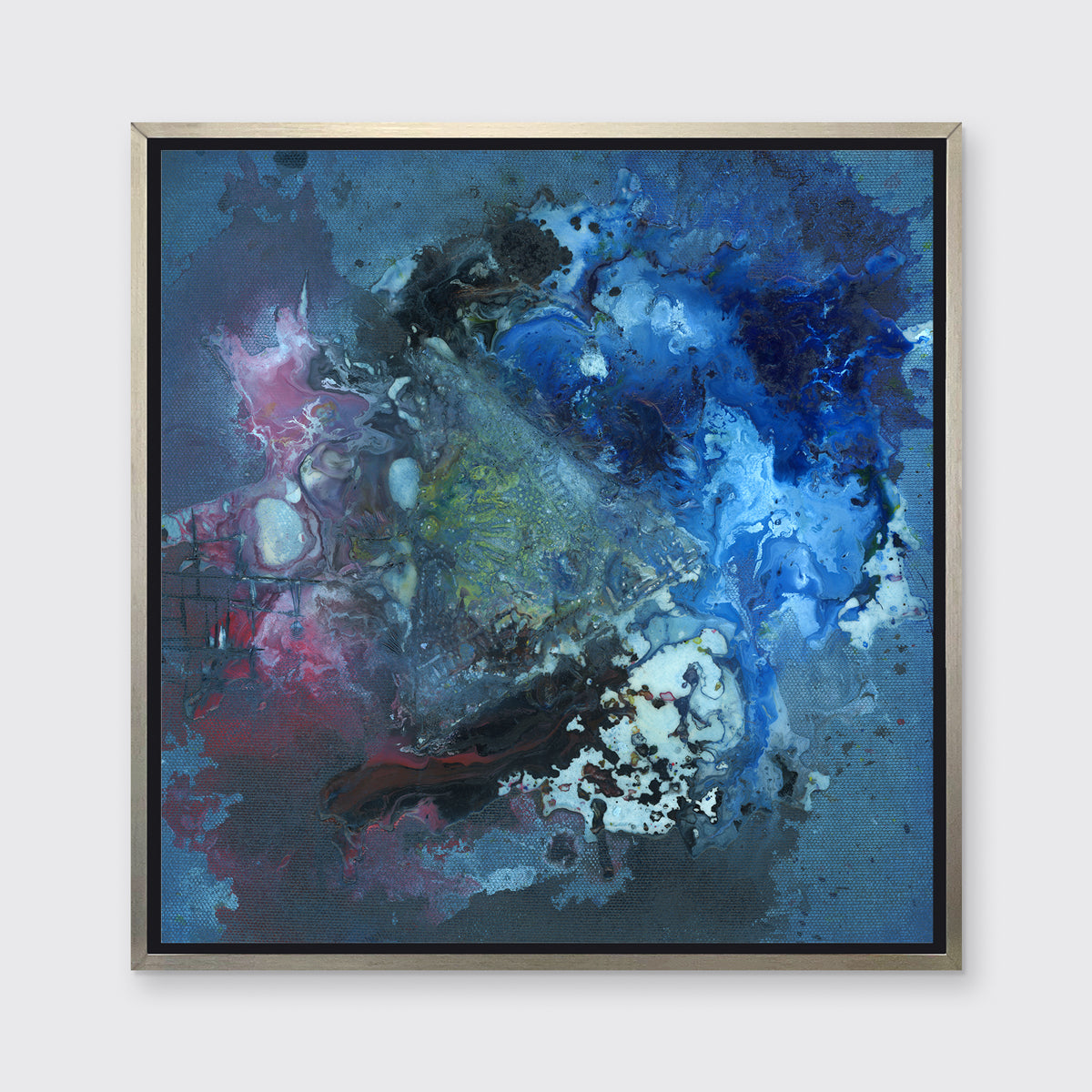 A blue, red, black and green abstract print in a silver floater frame hangs on a white wall.