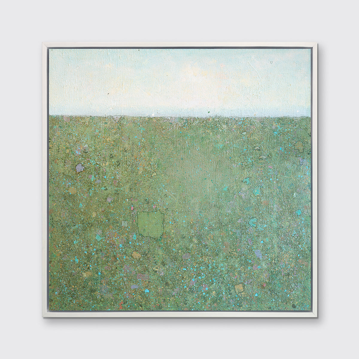 A green and blue abstract landscape print in a white floater frame hangs on a white wall.