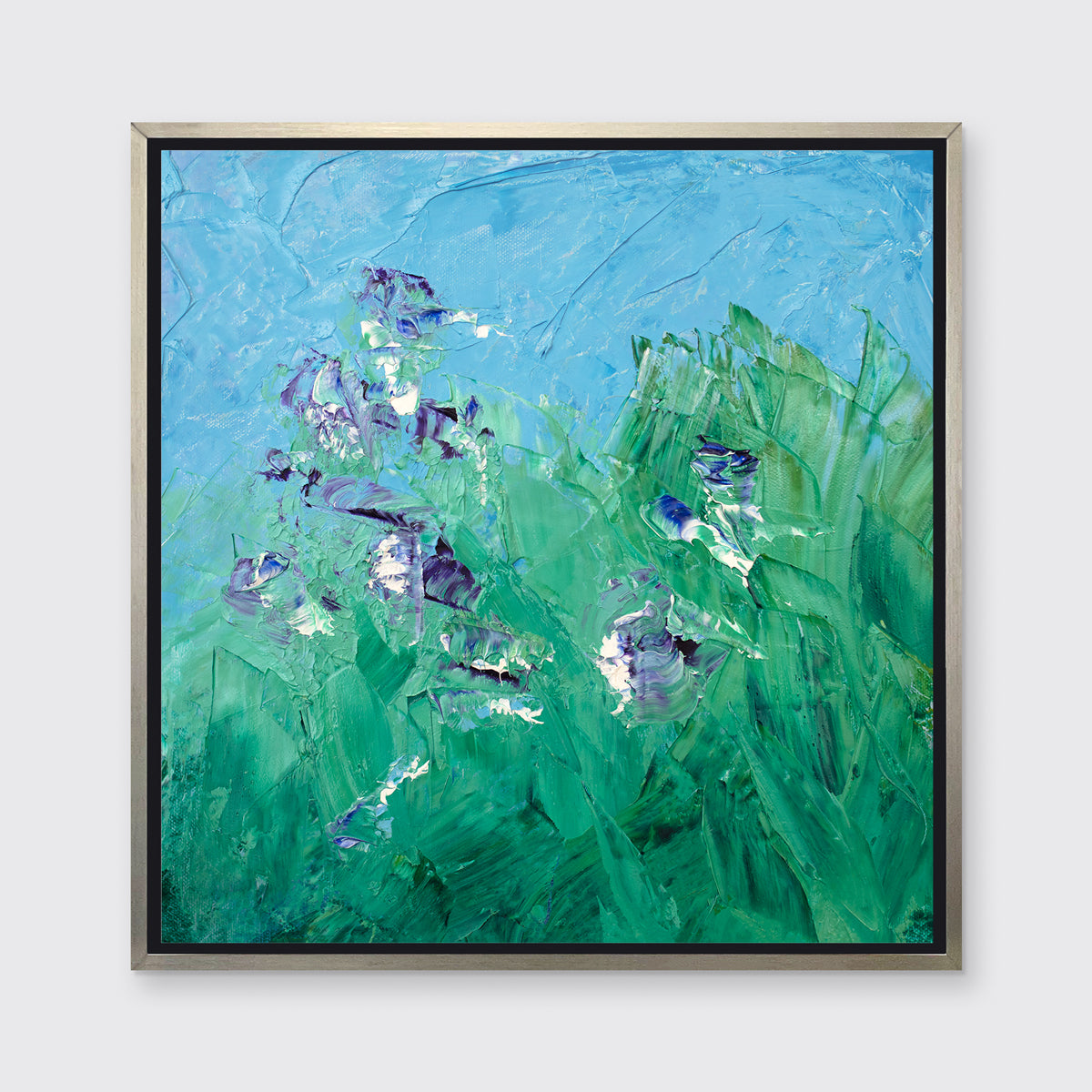 A blue, green, purple and white abstract landscape print in a silver floater frame hangs on a white wall.