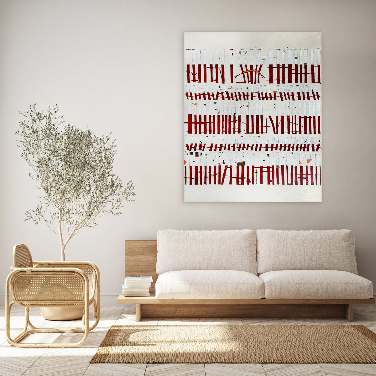 An abstract painting of red and white vertical lines with hints of orange on a beige background hangs on a light beige wall above a minimal wood sofa with beige cushions and a wicker arm chair to the left.