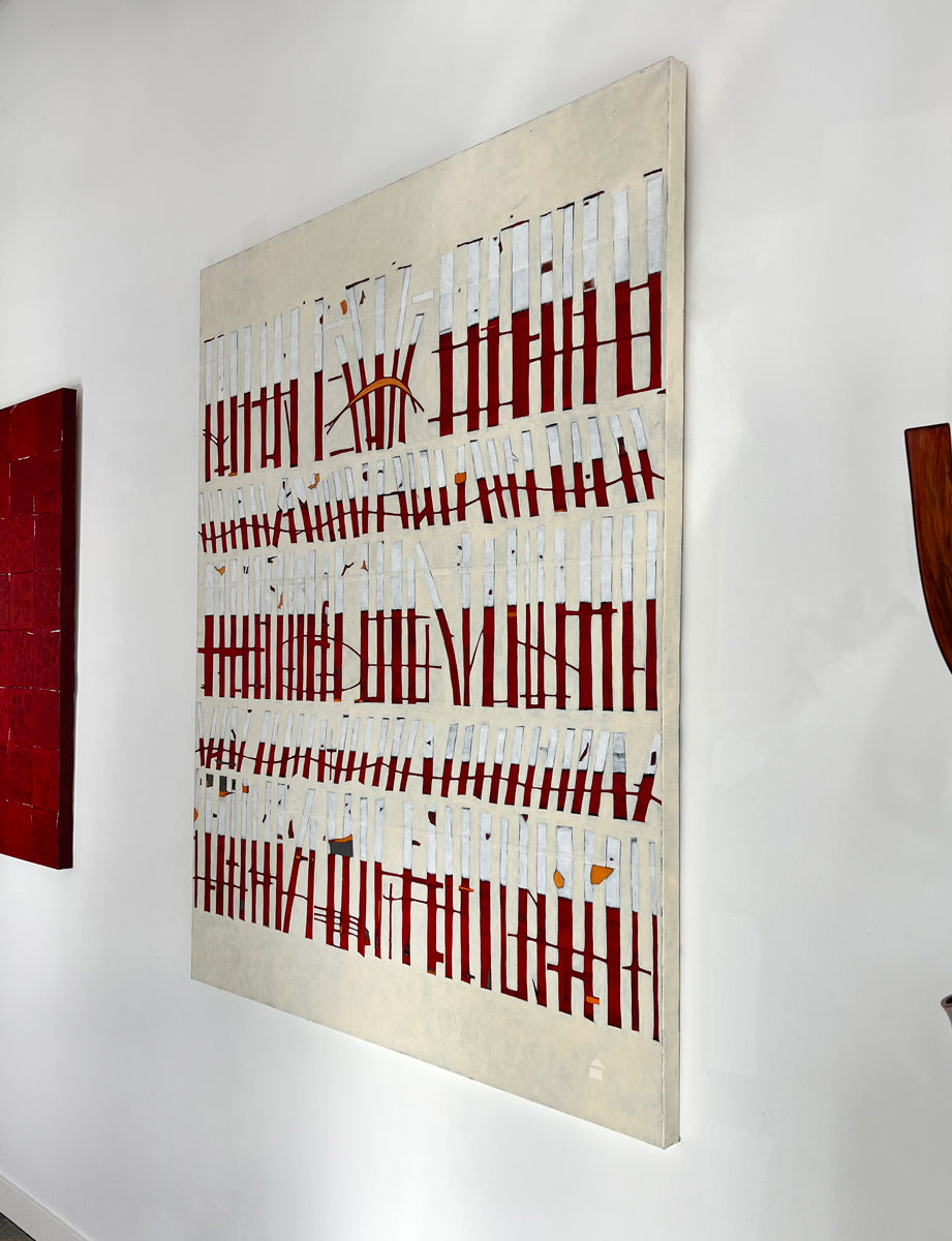 An abstract painting of red and white vertical lines with hints of orange on a beige background hangs on a white wall with a view from the right.