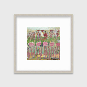 A green, pink and teal abstract floral print in a silver frame with a mat hangs on a white wall.