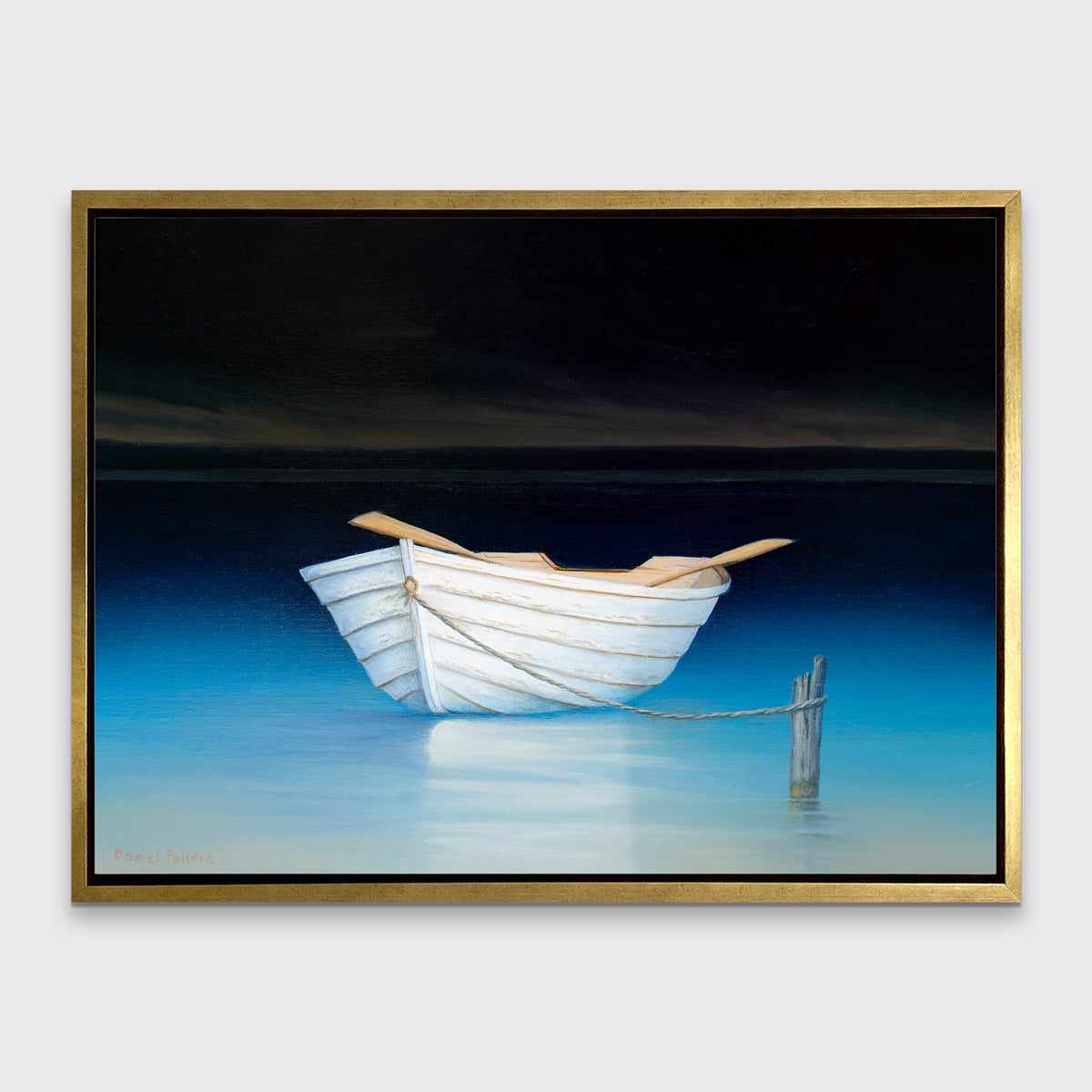 A contemporary realist print of a white rowboat alone on dark water against a dark sky in a gold floater frame hangs on a white wall.