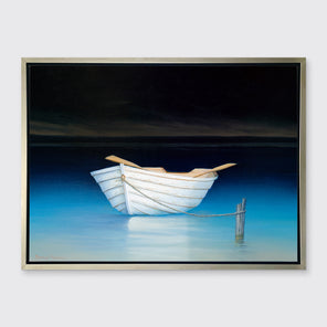 A contemporary realist print of a white rowboat alone on dark water against a dark sky in a silver floater frame hangs on a white wall.