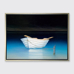 A contemporary realist print of a white rowboat alone on dark water against a dark sky in a silver floater frame hangs on a white wall.