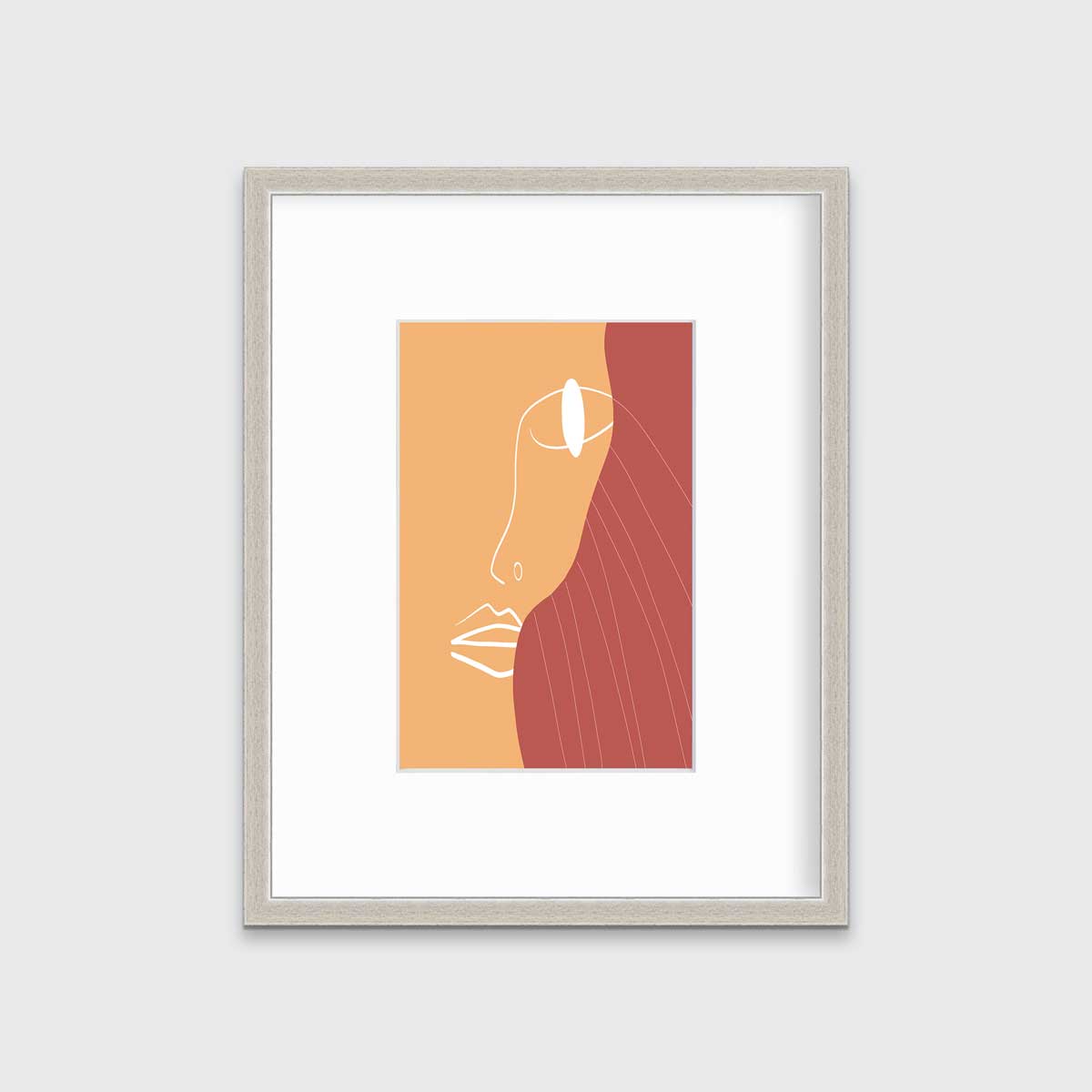 An abstract print with an outline of a woman's face in white and terracotta and beige organic shapes in the background in a silver frame with a mat hangs on a white wall.
