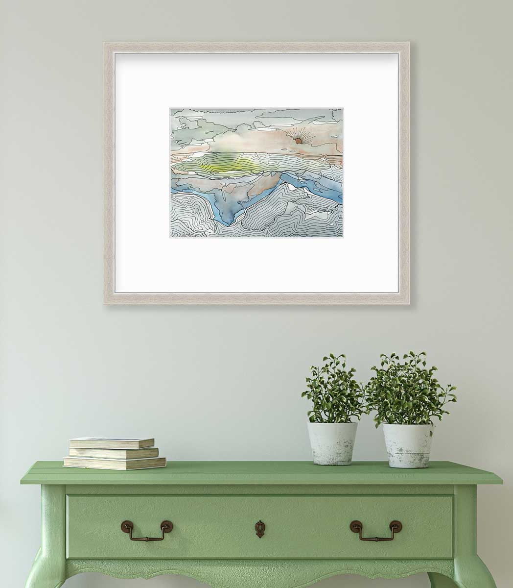 A brown, grey and light green abstract landscape print in a silver frame with a mat hangs on a white wall above a green console table with a stack of books and two potted plants.