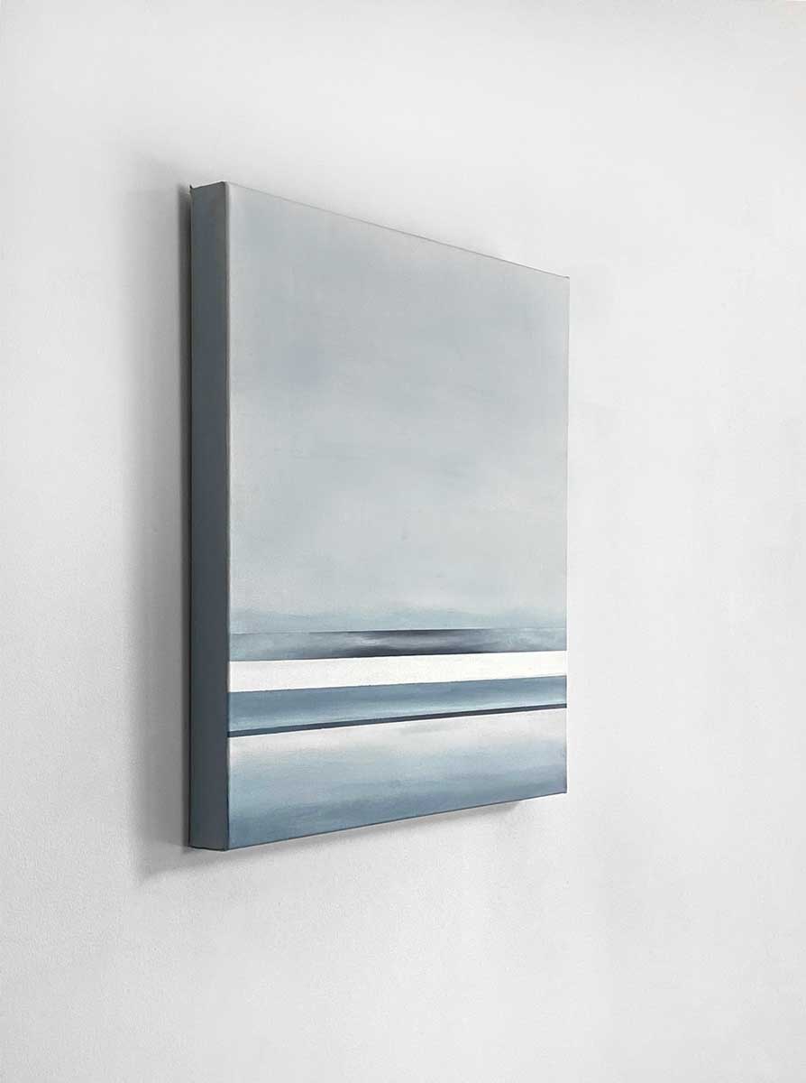 Side-angle view of an abstract painting featuring blue and white horizontal lines below a grey color block hangs on a white wall.