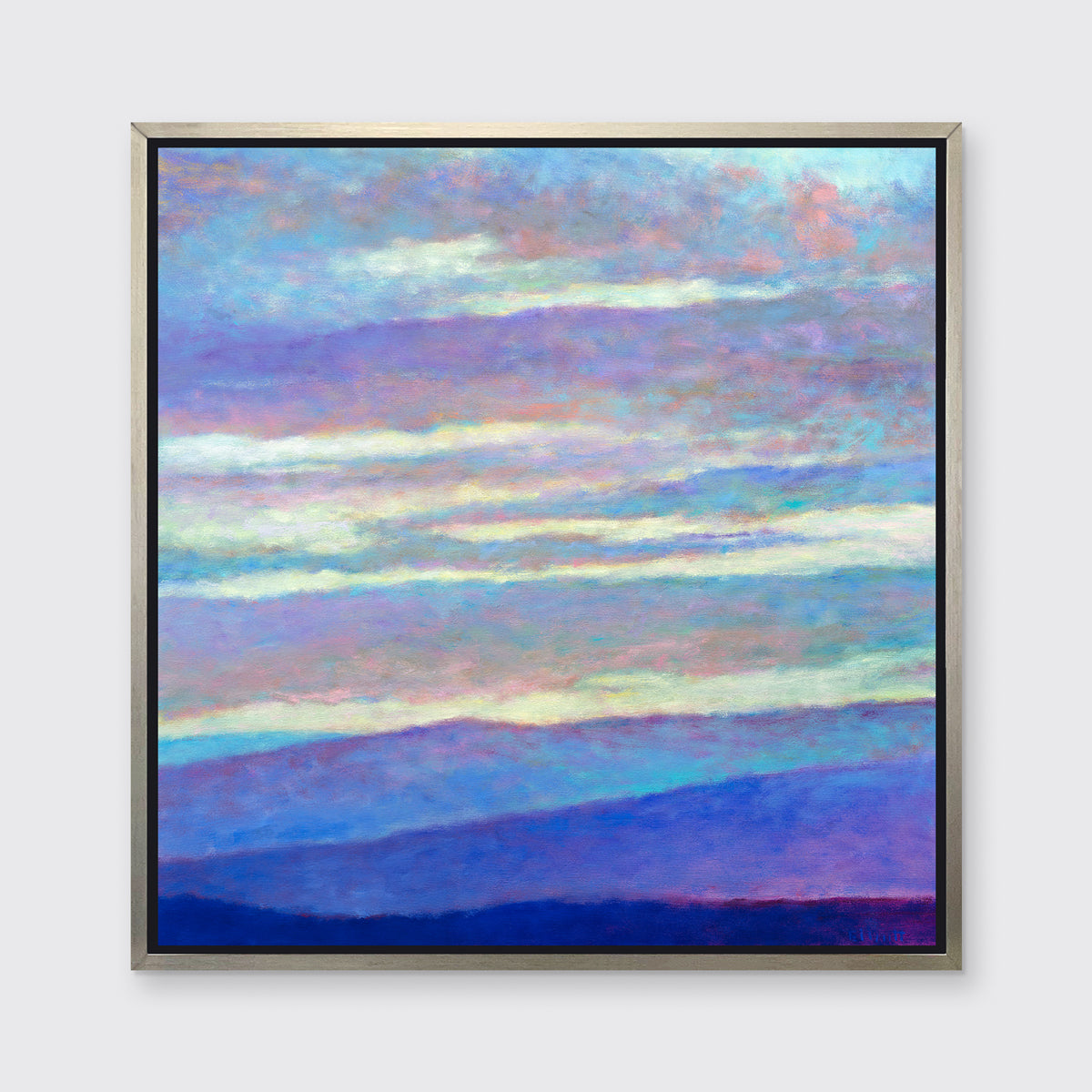 A blue, purple and light yellow abstract landscape print in a silver floater frame hangs on a white wall.