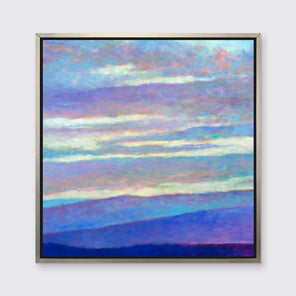 A blue, purple and light yellow abstract landscape print in a silver floater frame hangs on a white wall.