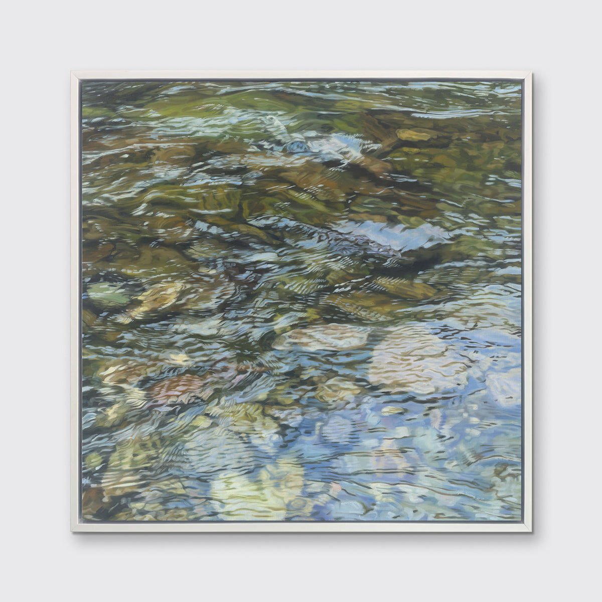 A green, brown, beige and white abstract river rock in water print in a white floater frame hangs on a white wall.