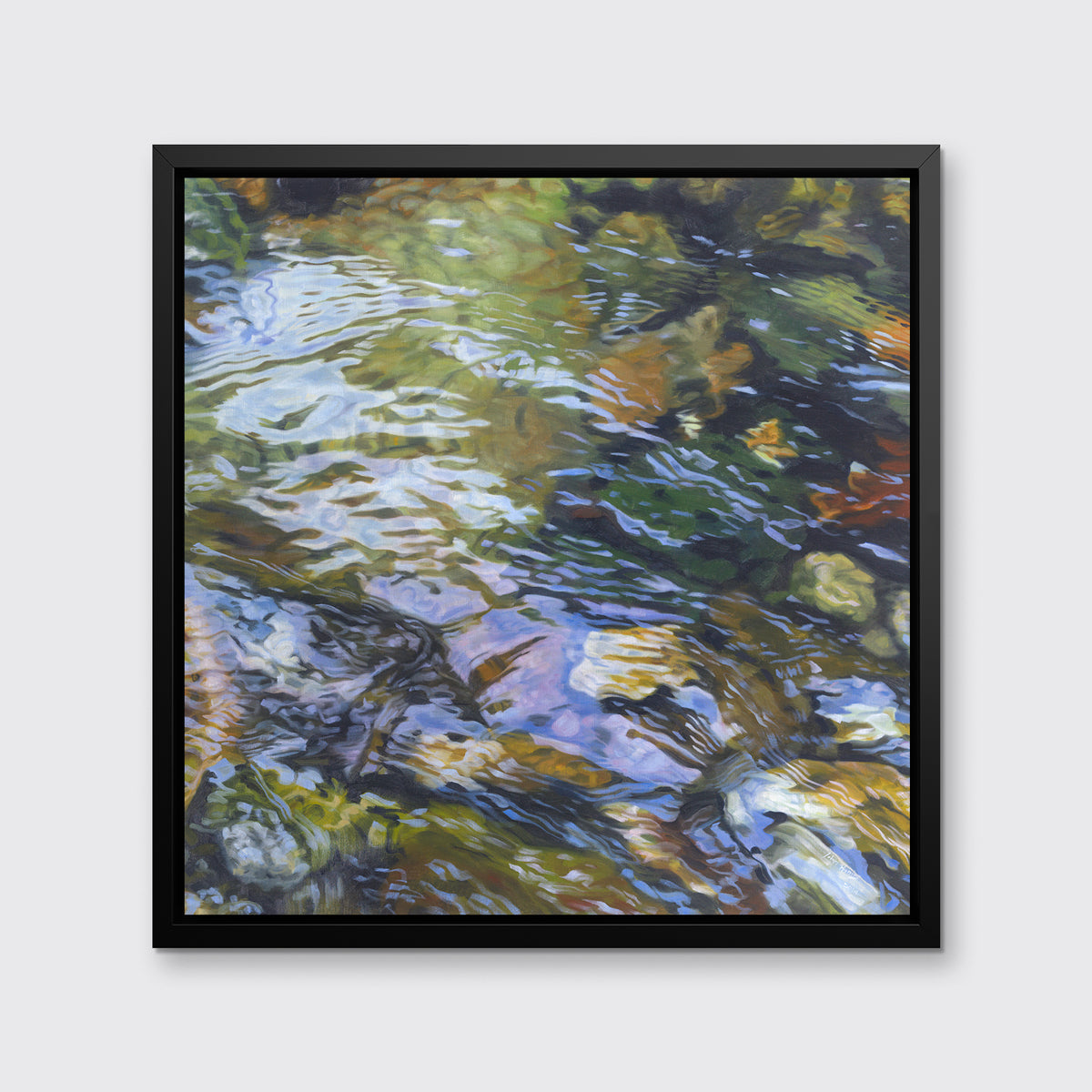A green, brown and beige abstract river rock in water print in a black floater frame hangs on a white wall.