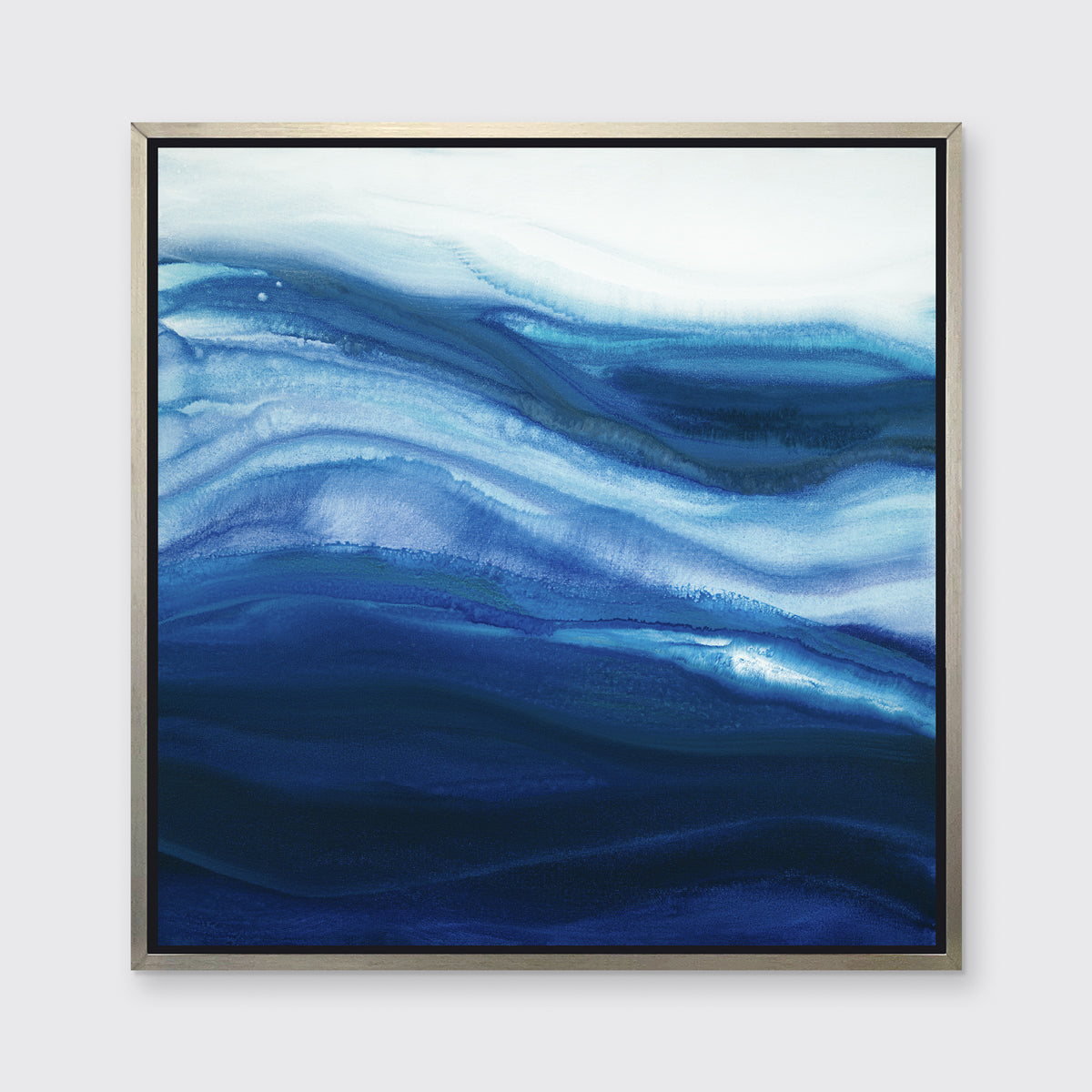 A blue, teal and white abstract print in a silver floater frame hangs on a white wall.