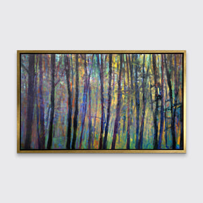 A multicolored abstract tree landscape print in a gold floater frame hangs on a white wall.