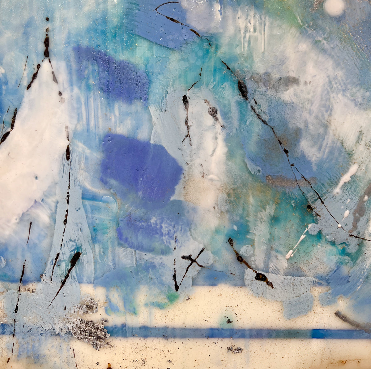 A detailed look at an encaustic painting with blue and turquoise marks.