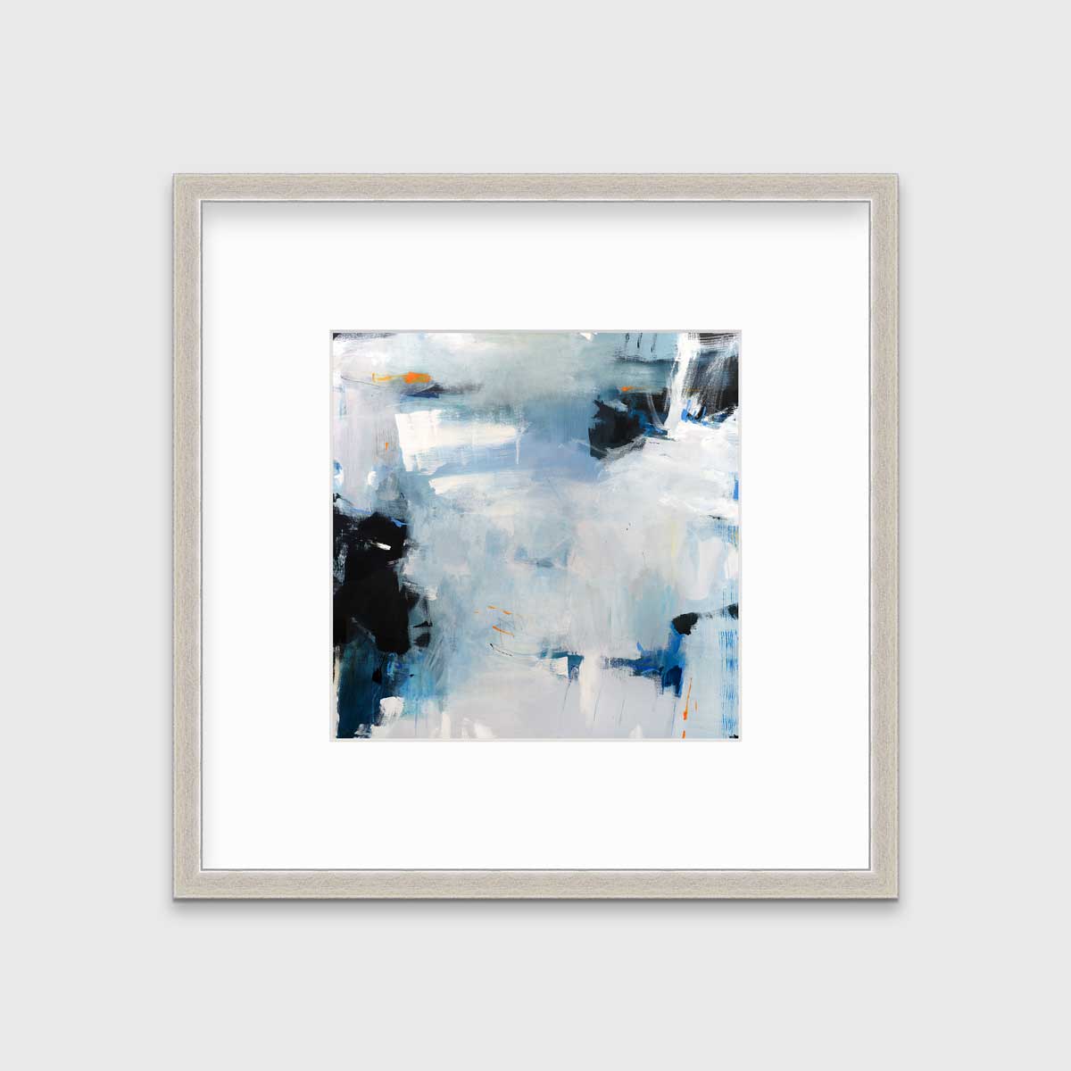 A blue and white abstract print in a silver frame with a mat hangs on a white wall.