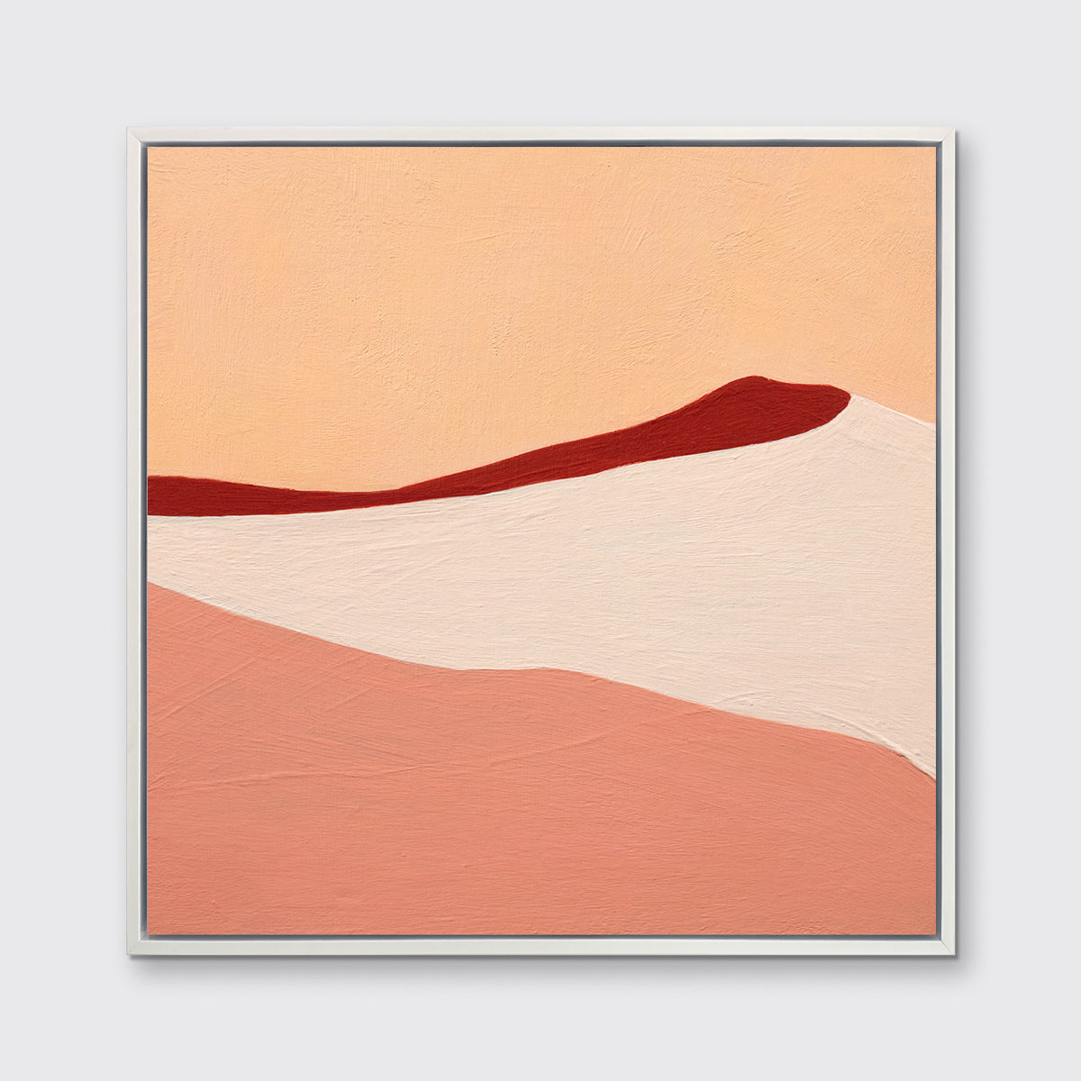 A red, peach and beige abstract print in a white floater frame hangs on a white wall.