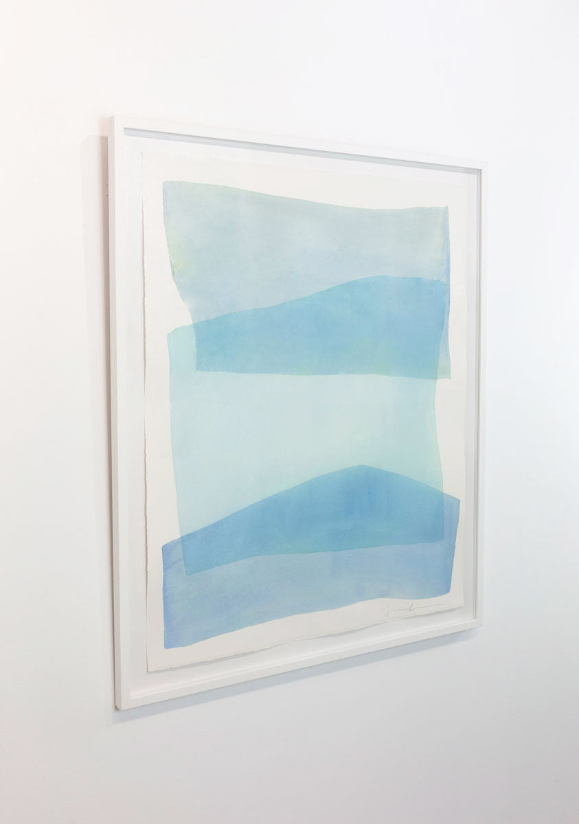 A watercolor painting of blue and turquoise stacked forms painted by Nealy Hauschildt is seen at an angle on a gallery wall.